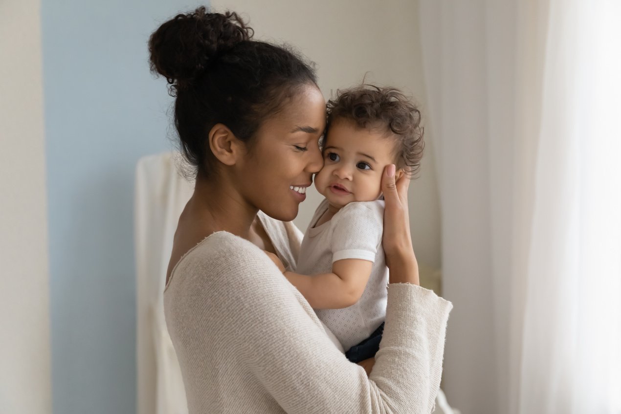 Happy African American mom embrace little baby toddler